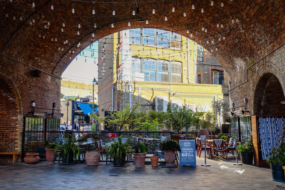 Inside a modern train station with a striking, architecturally intricate ceiling made of a lattice of white, curved steel beams illuminated by purple and white lighting. The station's interior feature