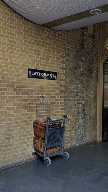 Outside a brick building at King's Cross, a luggage trolley is parked against the wall, carrying a vintage brown suitcase and a smaller matching bag. Above the trolley, a black sign with white letteri